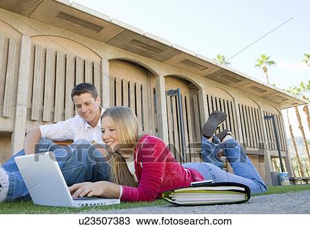 Stock Image - Two students using laptop outdoors. Fotosearch