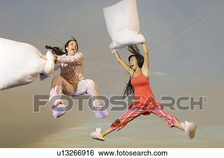 Two women having pillow fight mid-air outdoors View Large Photo Image Stock Photograph - Two women having pillow fight mid-air outdoors. Fotosearch