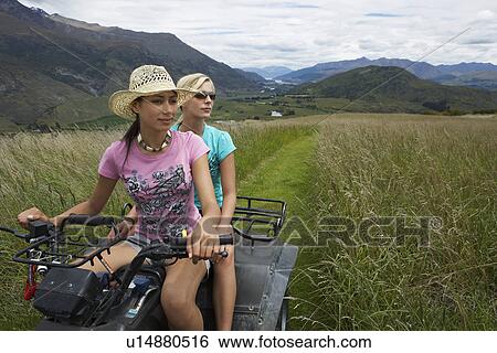 Two women riding four-wheeler through field View Large Photo Image Stock Photograph - Two women riding four-wheeler through field. Fotosearch