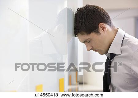 Unhappy Businessman resting head against office wall side view View Large Photo Image Stock Photo - Unhappy Businessman resting head against office wall side view. Fotosearch
