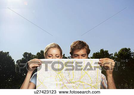 Stock Image - Vacationing couple in park looking at large map. Fotosearch