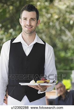 Stock Photo - Waiter holding slice of pie at outdoor cafe. Fotosearch