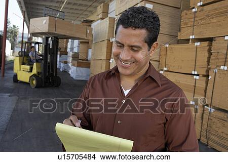 Picture - Warehouse Worker in front of man working with forklift. Fotosearch
