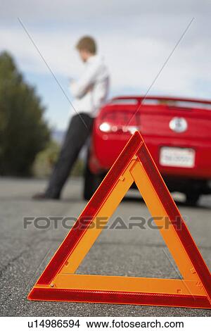 Warning triangle standing by man leaning on broken down car View Large Photo Image Picture - Warning triangle standing by man leaning on broken down car. Fotosearch