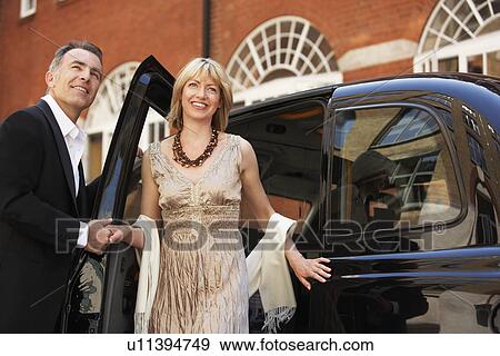 Well dressed couple exiting London taxi View Large Photo Image Stock Photo - Well dressed couple exiting London taxi. Fotosearch