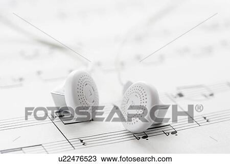 Stock Image - White headphones on sheet music. Fotosearch