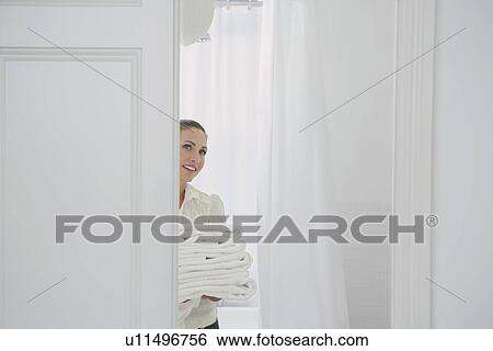 Stock Photograph - Woman carrying folded linen in home. Fotosearch