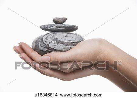 Picture - Woman holding pile of stones close-up on hands. Fotosearch