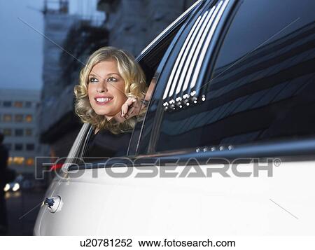 Stock Image - Woman in back of limousine looking out of window. Fotosearch
