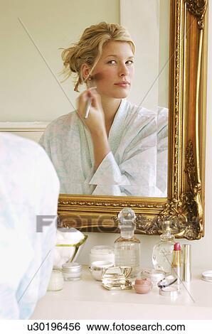Woman in bathrobe sitting Applying Make-up looking in mirror View Large Photo Image Stock Photograph - Woman in bathrobe sitting Applying Make-up looking in mirror. Fotosearch