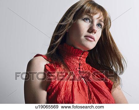 Stock Photo - Woman in red top in studio head and shoulders. Fotosearch