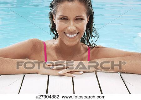 Stock Image - Woman in Swimming Pool resting on poolside portrait. Fotosearch