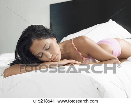 Stock Image - Woman in underwear sleeping on bed. Fotosearch