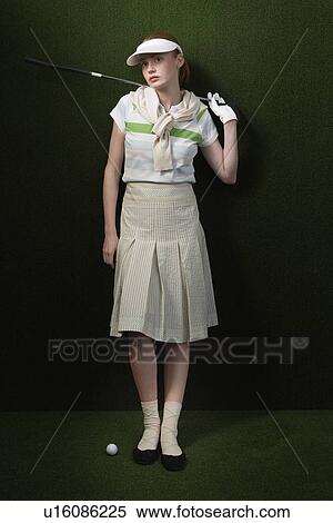 Stock Photography - Woman in visor holding golf club behind shoulders portrait. Fotosearch