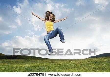 Woman jumping for joy in mountain meadow front view View Large Photo Image Stock Image - Woman jumping for joy in mountain meadow front view. Fotosearch