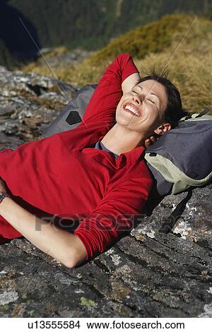 Woman laying on backpack on boulders View Large Photo Image Picture - Woman laying on backpack on boulders. Fotosearch