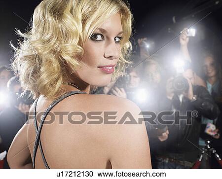 Stock Image - Woman looking over shoulder being photographed by paparazzi. Fotosearch