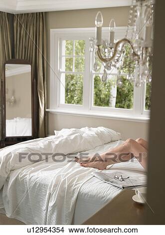 Woman lying in bed (low section) View Large Photo Image Picture - Woman lying in bed (low section). Fotosearch