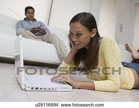 Woman lying on floor Using Laptop in living room ground view View Large Photo Image Picture - Woman lying on floor Using Laptop in living room ground view. Fotosearch