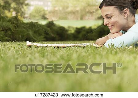 Woman lying on grass reading newspaper side view. View Large Photo Image Stock Image - Woman lying on grass reading newspaper side view.. Fotosearch