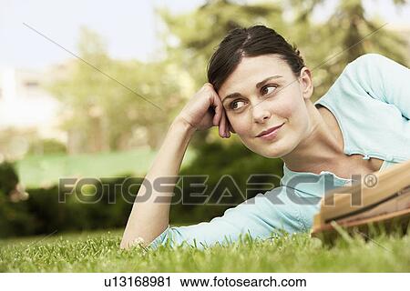 Woman lying on grass with newspaper. View Large Photo Image Stock Image - Woman lying on grass with newspaper.. Fotosearch