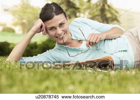 Woman lying on grass with newspaper holding glasses portrait. View Large Photo Image Stock Photography - Woman lying on grass with newspaper holding glasses portrait.. Fotosearch