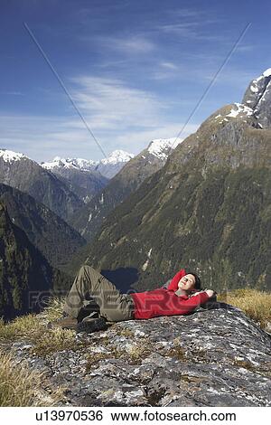 Stock Photograph - Woman lying on top of mountain peak. Fotosearch