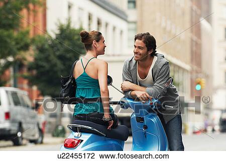 Woman on moped talking to man in street View Large Photo Image Stock Image - Woman on moped talking to man in street. Fotosearch