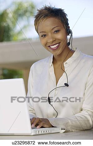 Woman on patio using laptop and headset portrait View Large Photo Image Stock Image - Woman on patio using laptop and headset portrait. Fotosearch