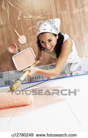 Woman painting interior wall with roller elevated view View Large Photo Image Stock Photo - Woman painting interior wall with roller elevated view. Fotosearch
