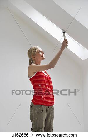 Stock Photo - Woman painting sloping ceiling. Fotosearch