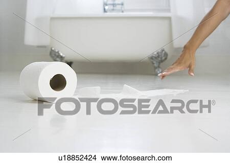 Picture - Woman reaching for toilet paper on bathroom floor. Fotosearch
