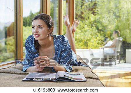 Woman reading magazine near windows overlooking forest View Large Photo Image Stock Image - Woman reading magazine near windows overlooking forest. Fotosearch