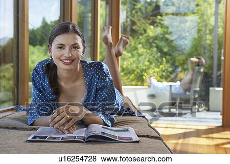 Woman reading magazine near windows overlooking forest View Large Photo Image Stock Photo - Woman reading magazine near windows overlooking forest. Fotosearch