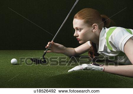 Woman reclining on floor holding golf club looking at golf ball View Large Photo Image Stock Image - Woman reclining on floor holding golf club looking at golf ball. Fotosearch