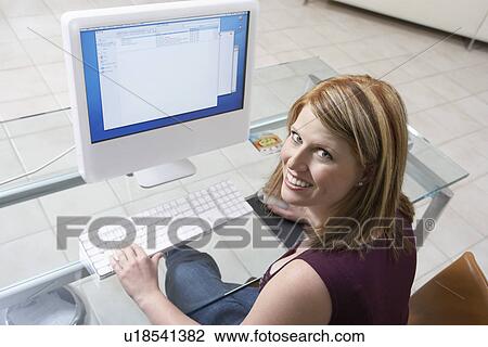 Woman sitting at computer (elevated view) View Large Photo Image Stock Image - Woman sitting at computer (elevated view). Fotosearch