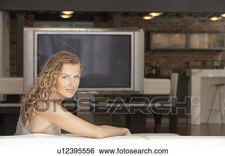 Woman sitting in modern living room plasma television in background portrait View Large Photo Image Stock Photograph - Woman sitting in modern living room plasma television in background portrait. Fotosearch