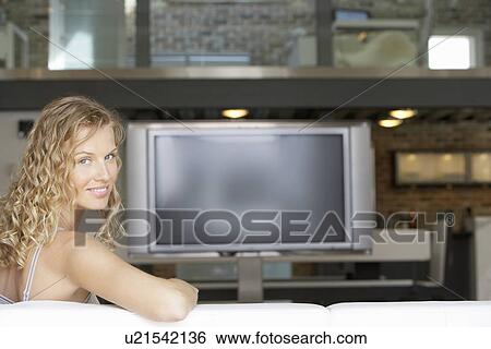 Woman sitting in modern living room plasma television in background portrait View Large Photo Image Stock Photograph - Woman sitting in modern living room plasma television in background portrait. Fotosearch