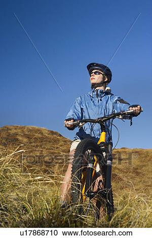 Woman sitting on bicycle in field View Large Photo Image Stock Image - Woman sitting on bicycle in field. Fotosearch
