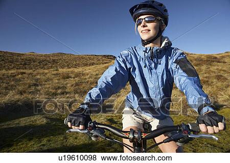 Woman sitting on bicycle in field View Large Photo Image Stock Photo - Woman sitting on bicycle in field. Fotosearch
