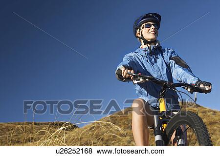 Woman sitting on bicycle in field View Large Photo Image Stock Photo - Woman sitting on bicycle in field. Fotosearch