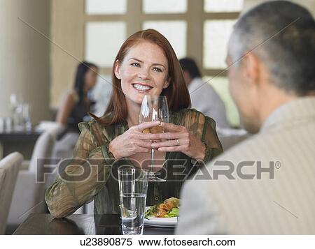 Stock Photography - Woman smiling at man over meal in restaurant. Fotosearch