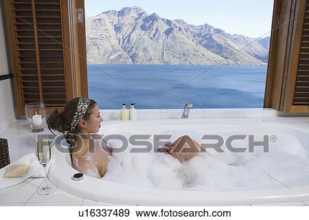 Woman taking a bubble bath with mountain lake outside window View Large Photo Image Stock Photo - Woman taking a bubble bath with mountain lake outside window. Fotosearch