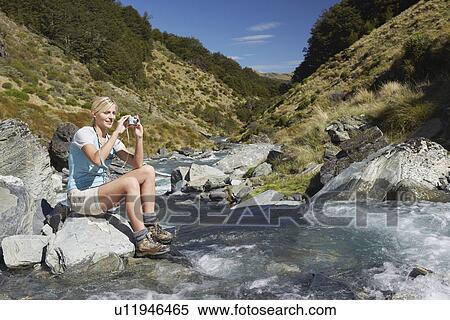 Woman taking picture of river in forest View Large Photo Image Stock Photography - Woman taking picture of river in forest. Fotosearch