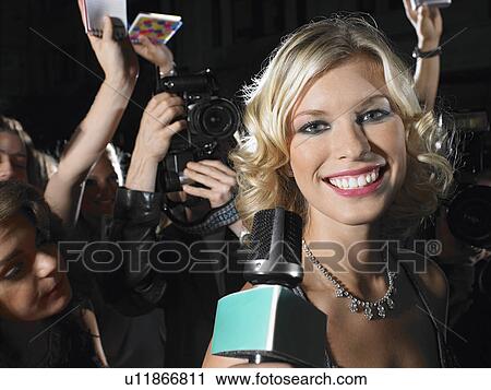 Stock Image - Woman talking into microphone on red carpet. Fotosearch