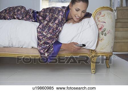 Stock Photography - Woman text messaging on bed. Fotosearch