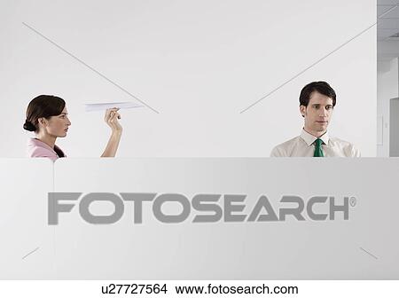 Woman throwing paper aeroplane at male colleague in office View Large Photo Image Picture - Woman throwing paper aeroplane at male colleague in office. Fotosearch