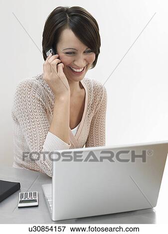 Woman using cell phone and laptop View Large Photo Image Stock Photo - Woman using cell phone and laptop. Fotosearch