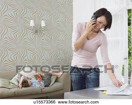 Stock Photograph - Woman using cell phone boy playing with toy. Fotosearch