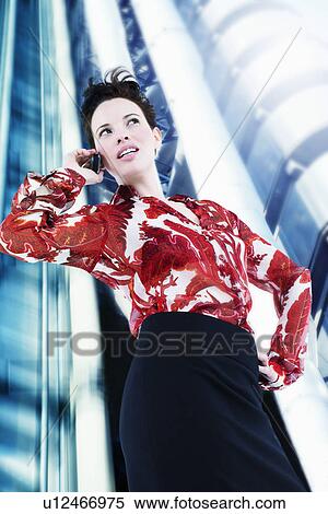 Stock Photography - Woman using cell phone in front of skyscraper. Fotosearch